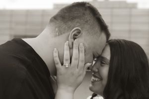 A romantic couple sharing an intimate kiss with hands covering their faces.