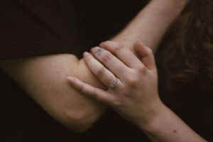 Intertwined hands showing gentle affection in dramatic lighting.