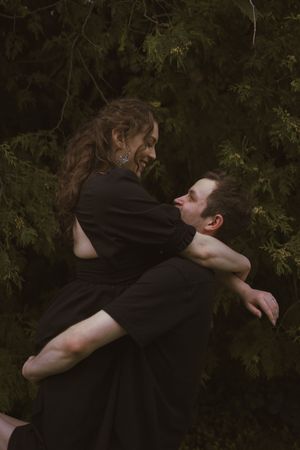 An emotional embrace captured in moody lighting with trees in background.