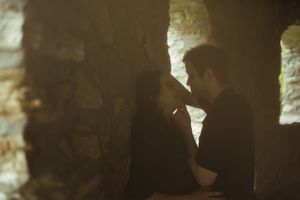 Silhouettes of a couple in a romantic pose against sunlit stone walls.