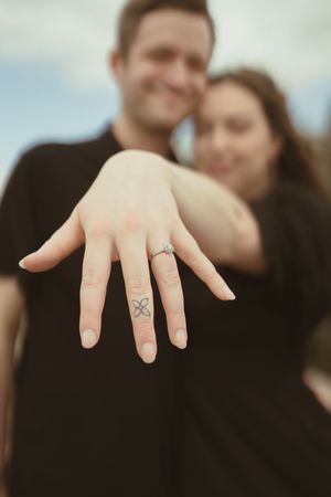 A close-up of hands showing engagement rings against a blurred background.