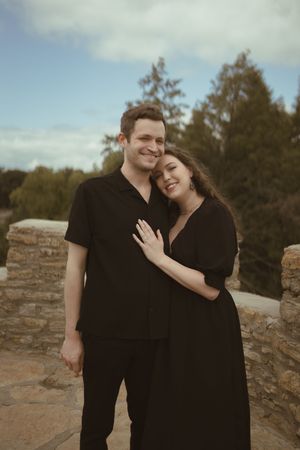 A couple in black clothing shares tender moments during their engagement photoshoot.