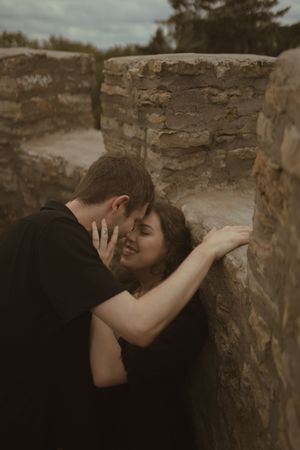An intimate moment captured between stone walls during an engagement photoshoot.
