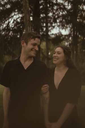 A joyful interaction between two people wearing black in a wooded setting.