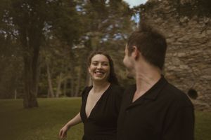Two people share genuine laughter during an outdoor photoshoot near stone ruins.