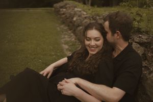 A romantic couple shares tender moments while sitting together in a park setting.