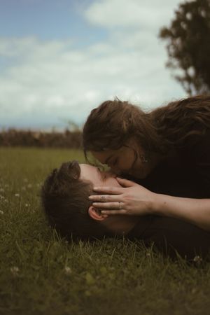 Artistic sequence of a person lying in grass with hands covering their face in moody lighting.
