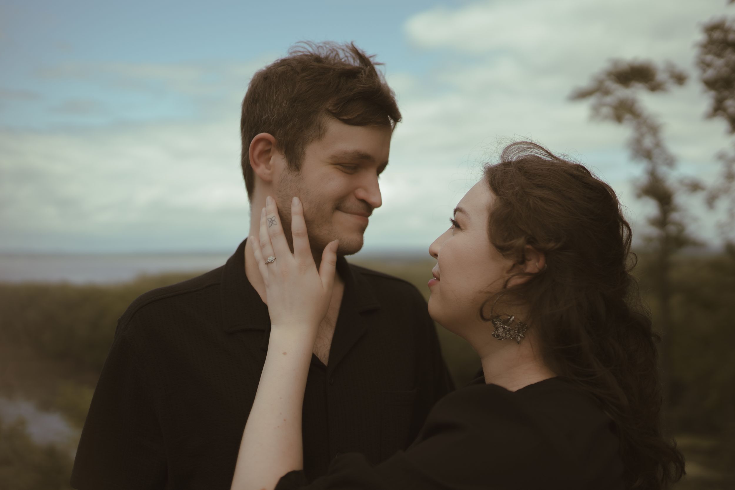 A couple shares an intimate moment against a scenic overlook.