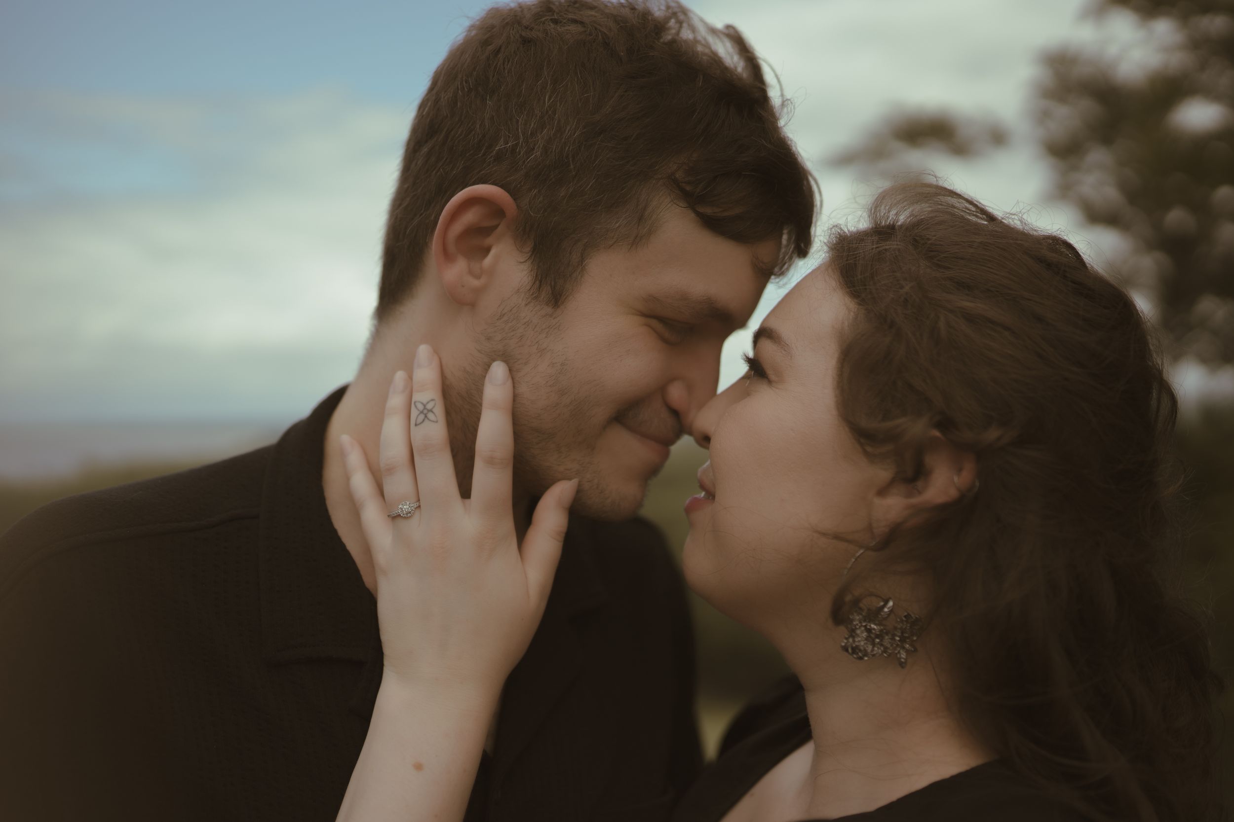 A romantic couple shares an intimate moment in a moody outdoor setting with dramatic lighting.