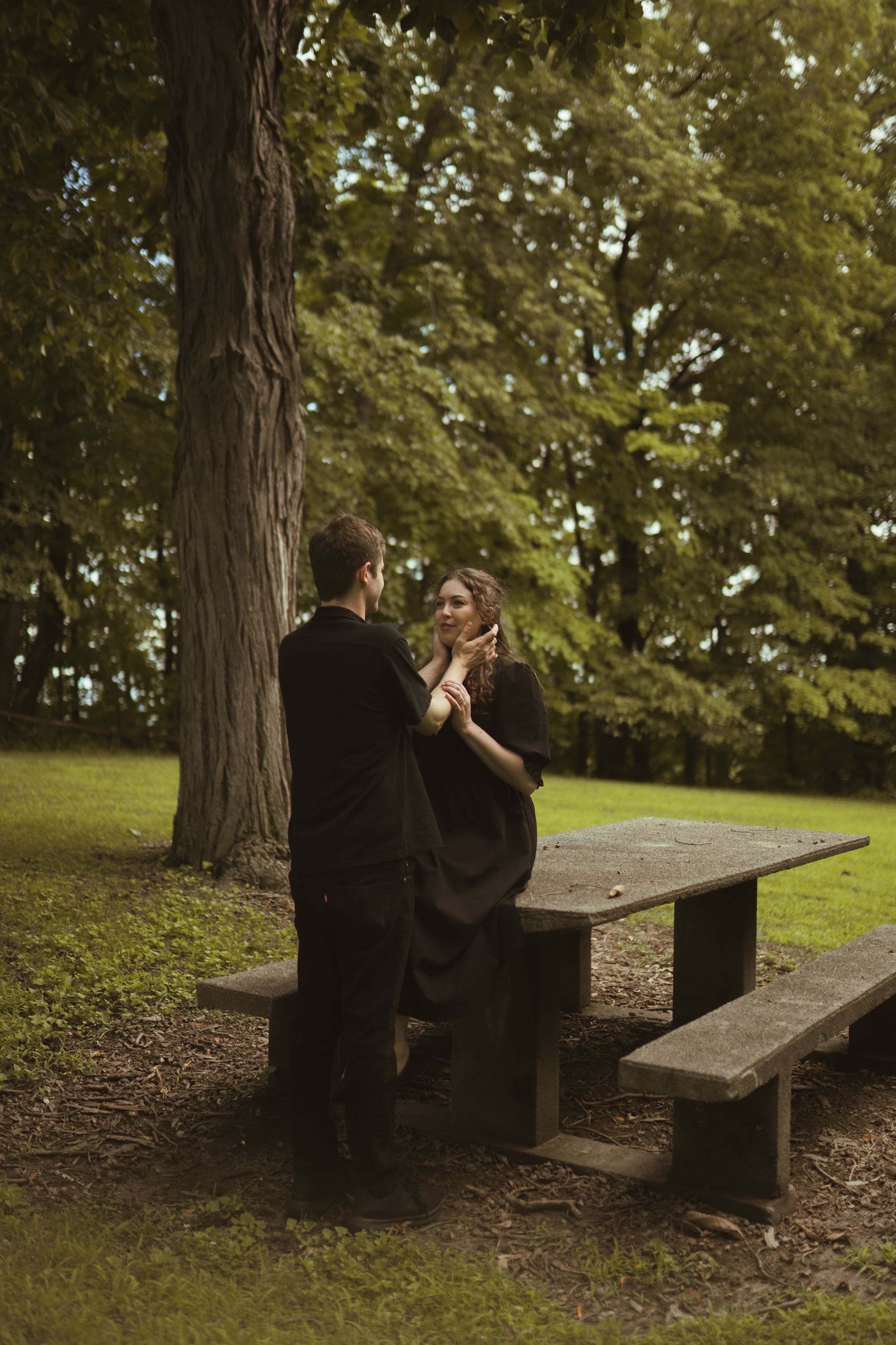 Wedding couple sharing a tender moment on wooden benches in a park setting.