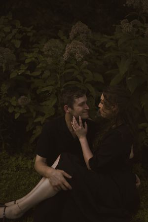 Two people in black clothing share an intimate embrace outdoors.