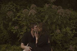 An artistic couples photo captured in a lush garden environment.