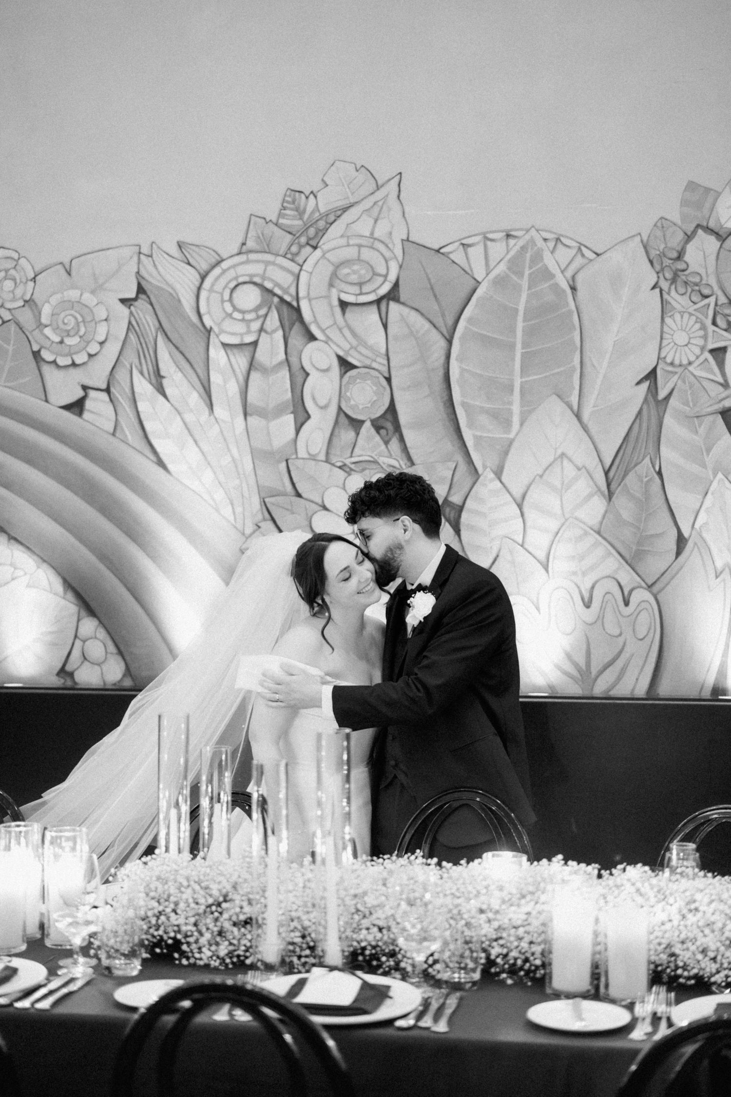 Black and white wedding reception photos showing a romantic moment against a backdrop of illuminated leaf decorations.
