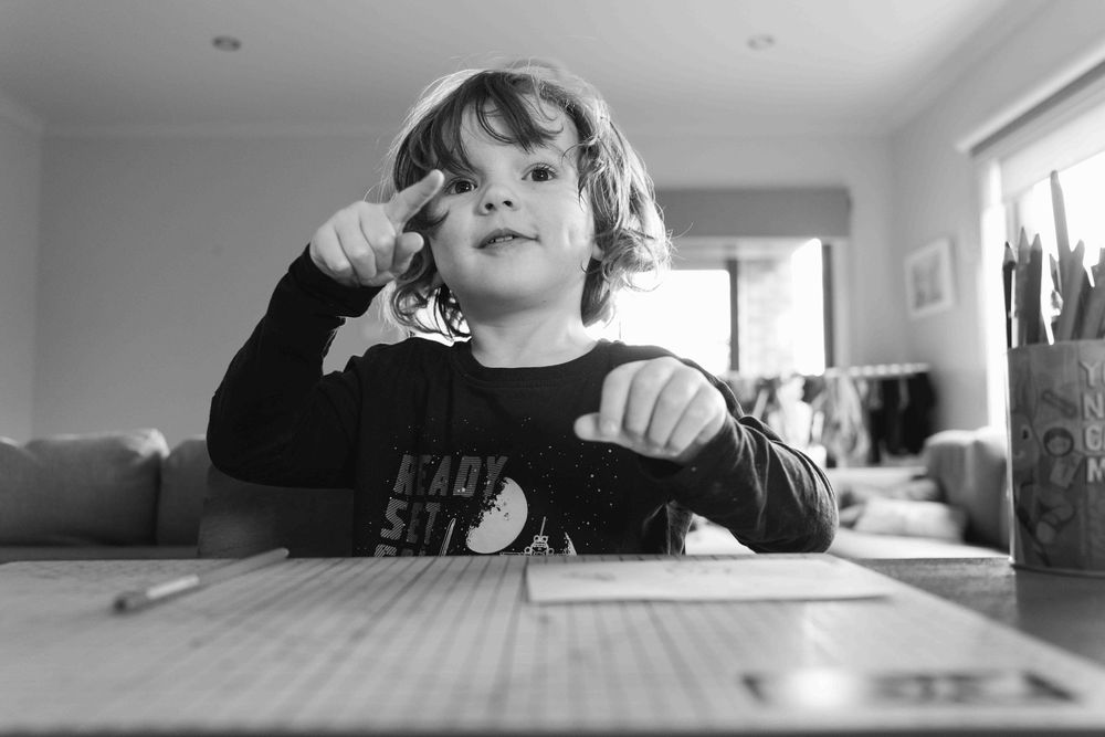 Young boy at the table pointing to something