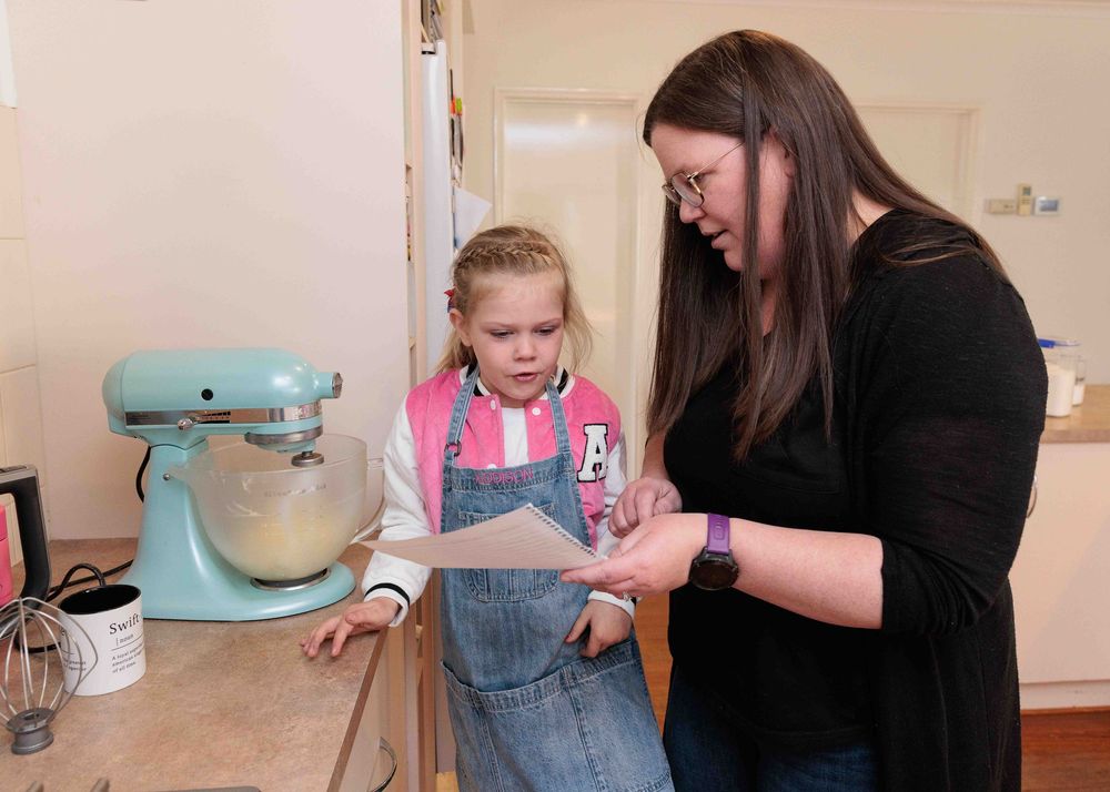 Mum and young girl reading a recipe in the kitchen.Leigh Ball, Documentary family photographer