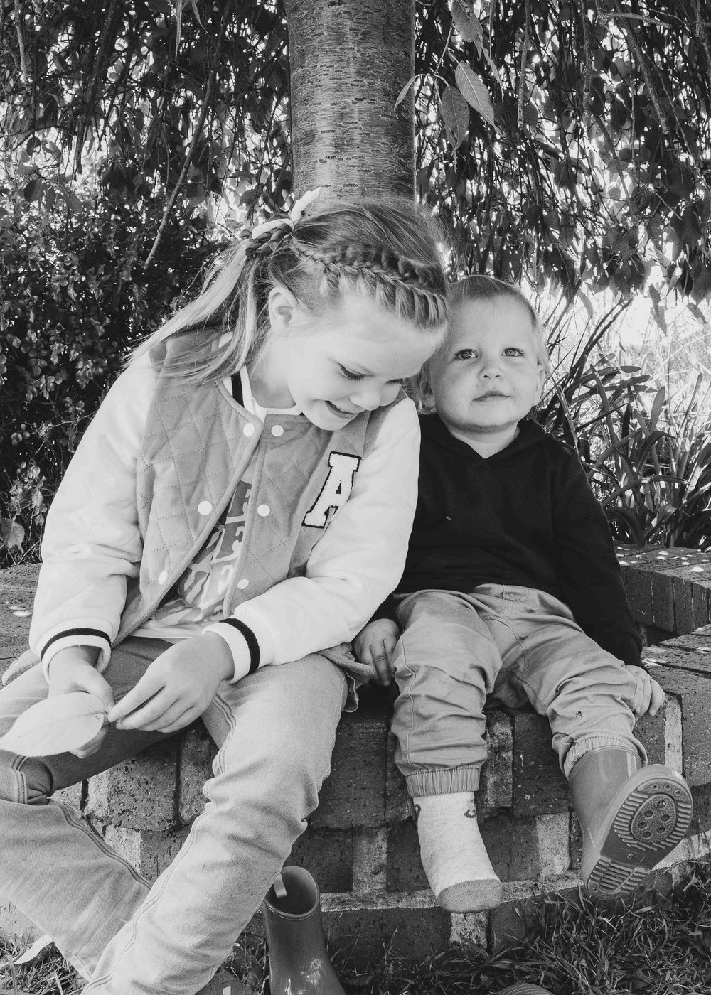 Unposed photo of siblings sitting under a tree.Leigh Ball, Documentary family photographer