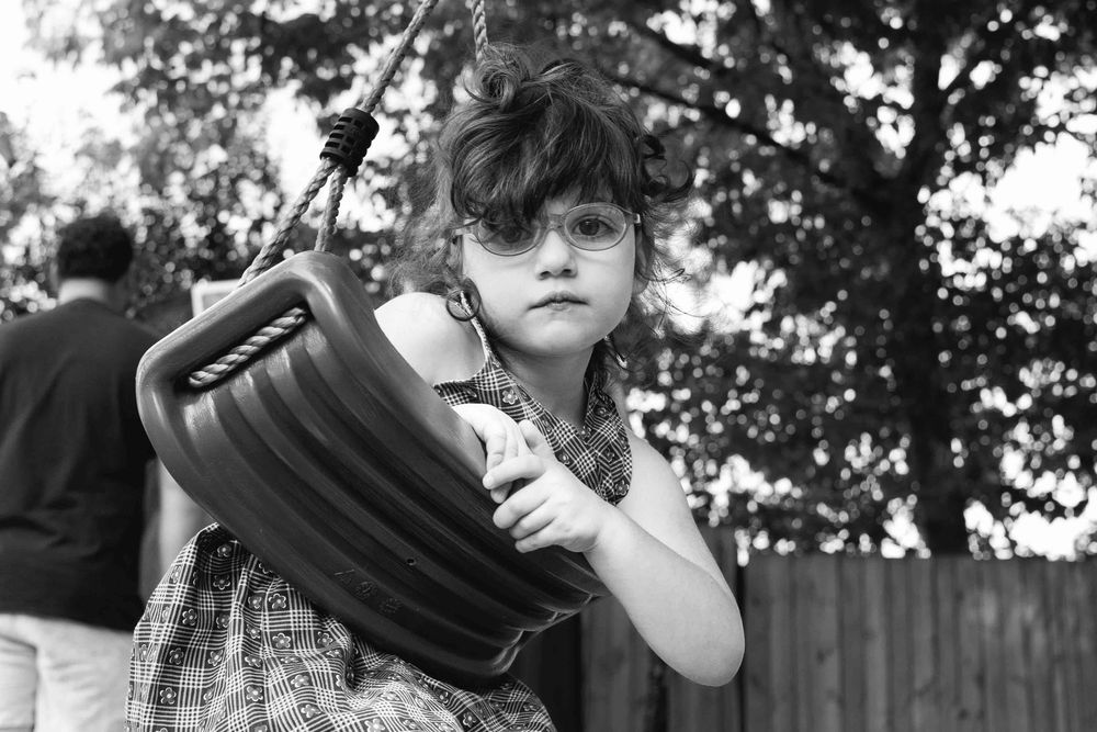 young girl gazing at the camera from the swing