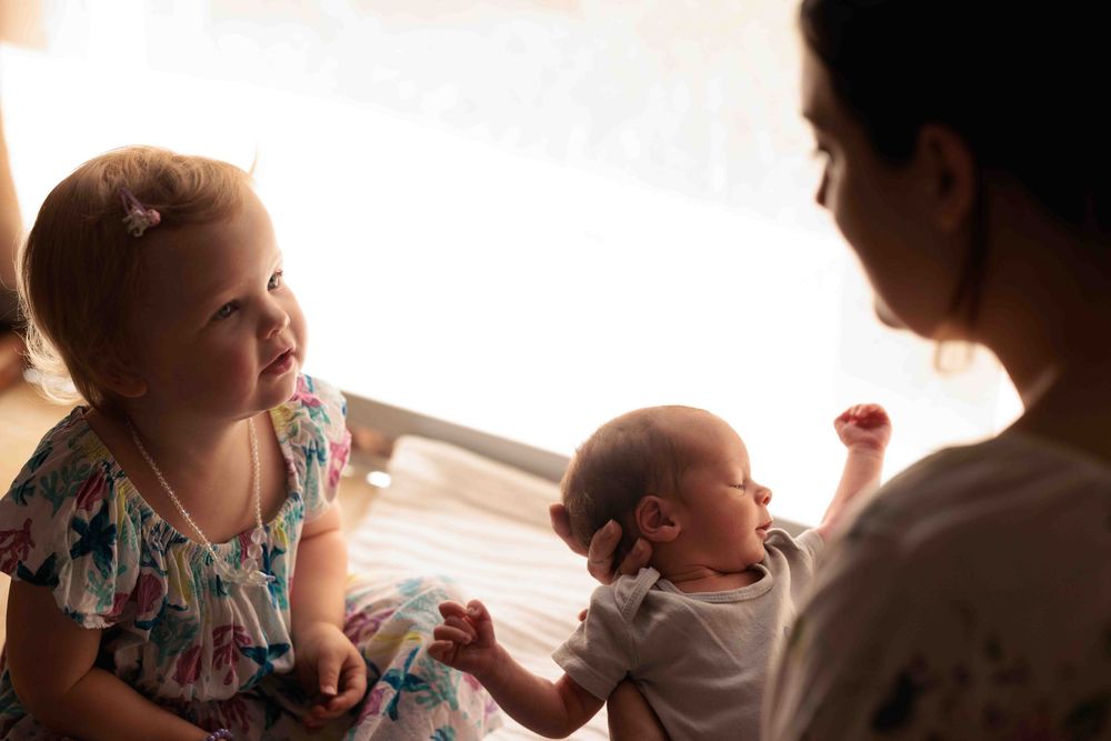 Toddler, Mum and newborn baby. sitting on floor.Leigh Ball, Documentary family photographer