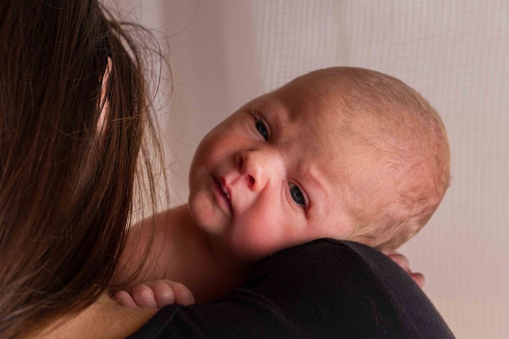 Newborn baby resting on Mum's shoulder.Leigh Ball, Documentary family photographer