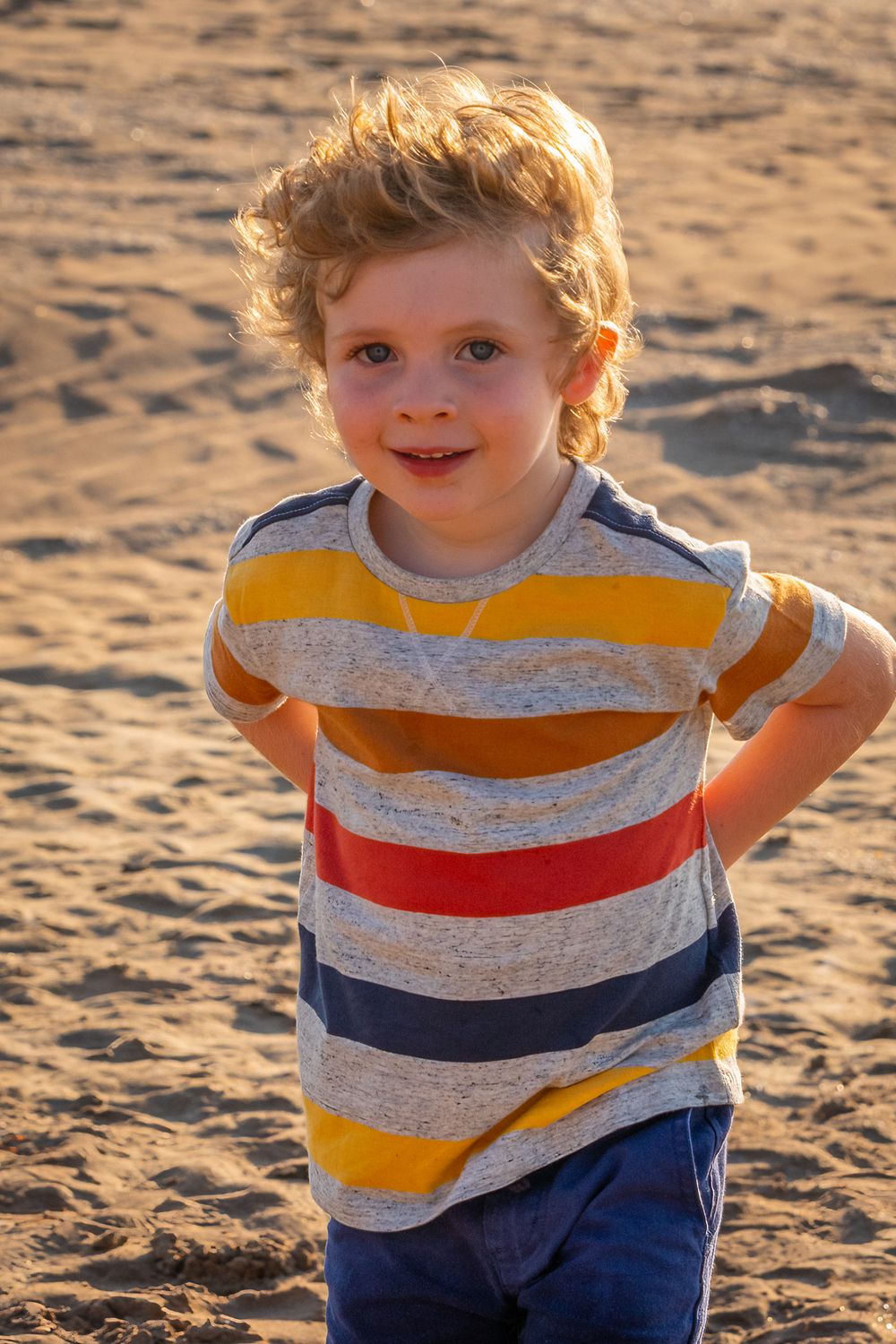 Young boy hides something behind his back at the beachLeigh Ball, Documentary family photographer
