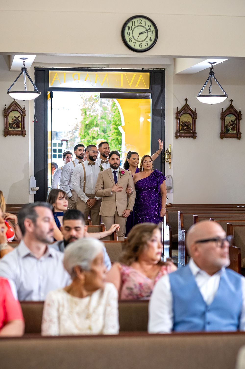 Wedding ceremony guests and bridal party seated in church pews during daytime service.