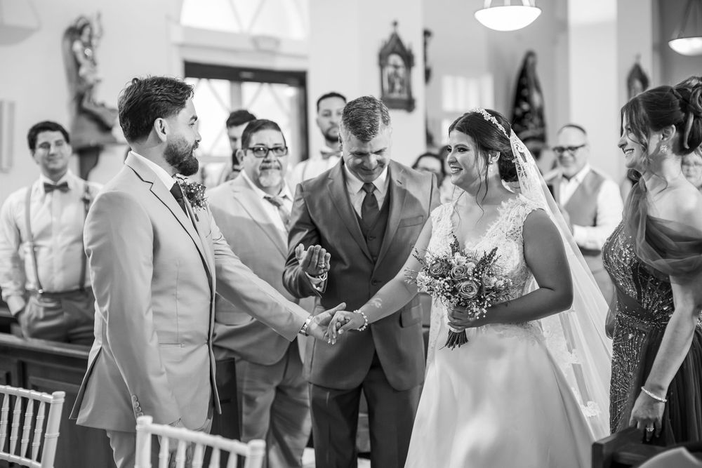 Black and white photo of a wedding ceremony taking place inside a church with guests gathered around.