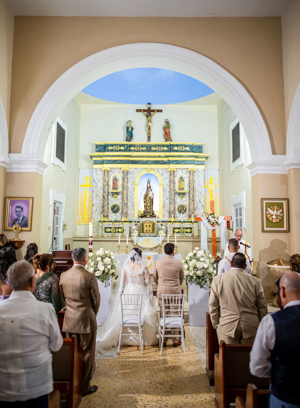 Church wedding ceremony taking place in a traditional Catholic chapel with ornate altar and arched architecture.