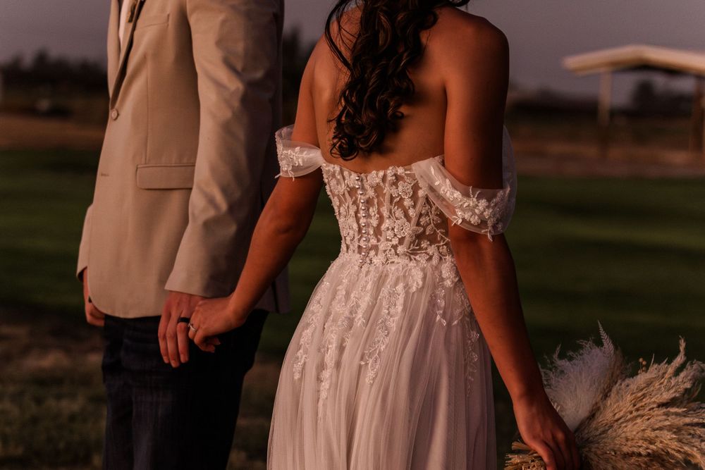 Sunset silhouettes of newlyweds in western-themed wedding attire.