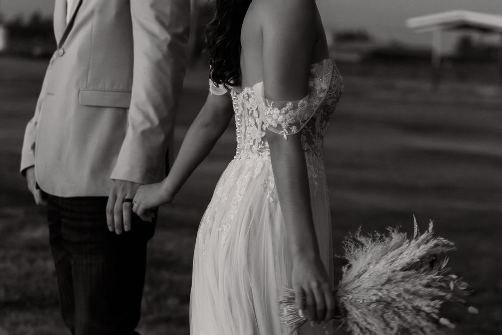 Couple in wedding attire walks together during golden hour.