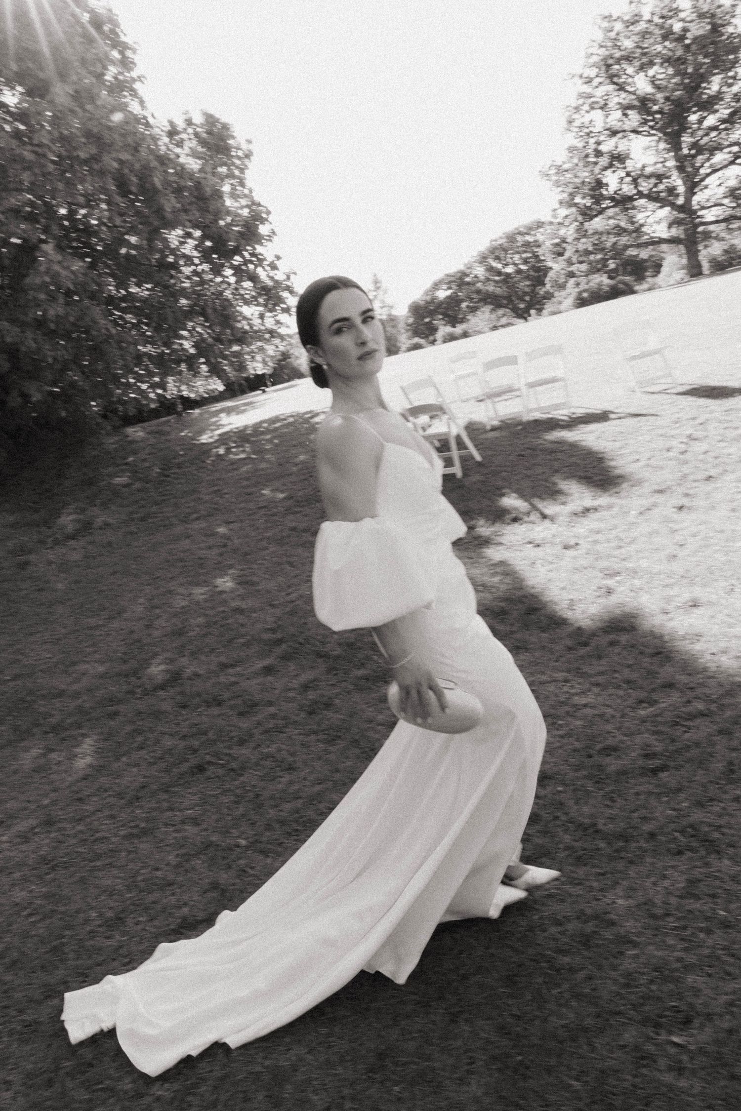 A black and white photo of an elegant wedding dress with billowing sleeves captured outdoors in natural lighting.