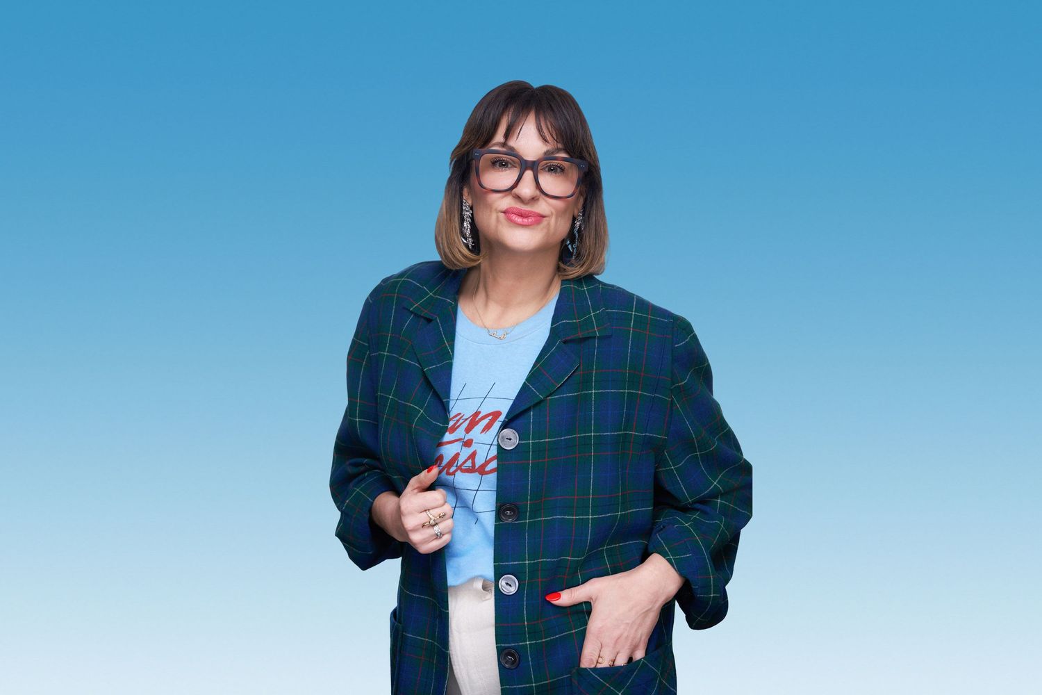 Person wearing glasses and plaid jacket poses against blue gradient background.
