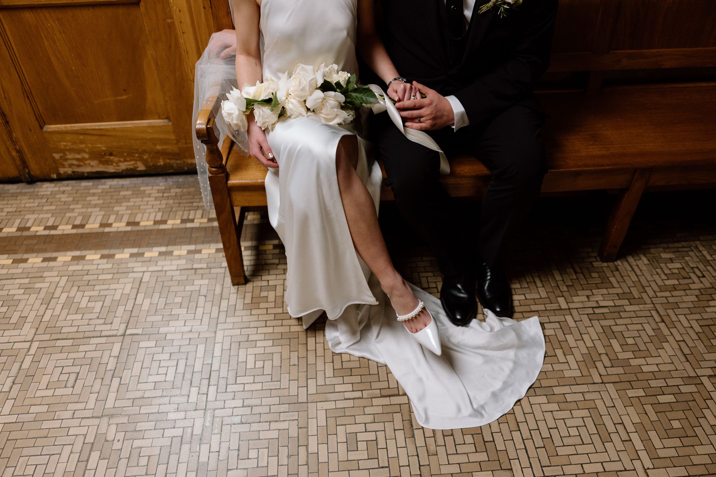 Bride and groom's feet shown side by side on a patterned carpet during intimate wedding moments.