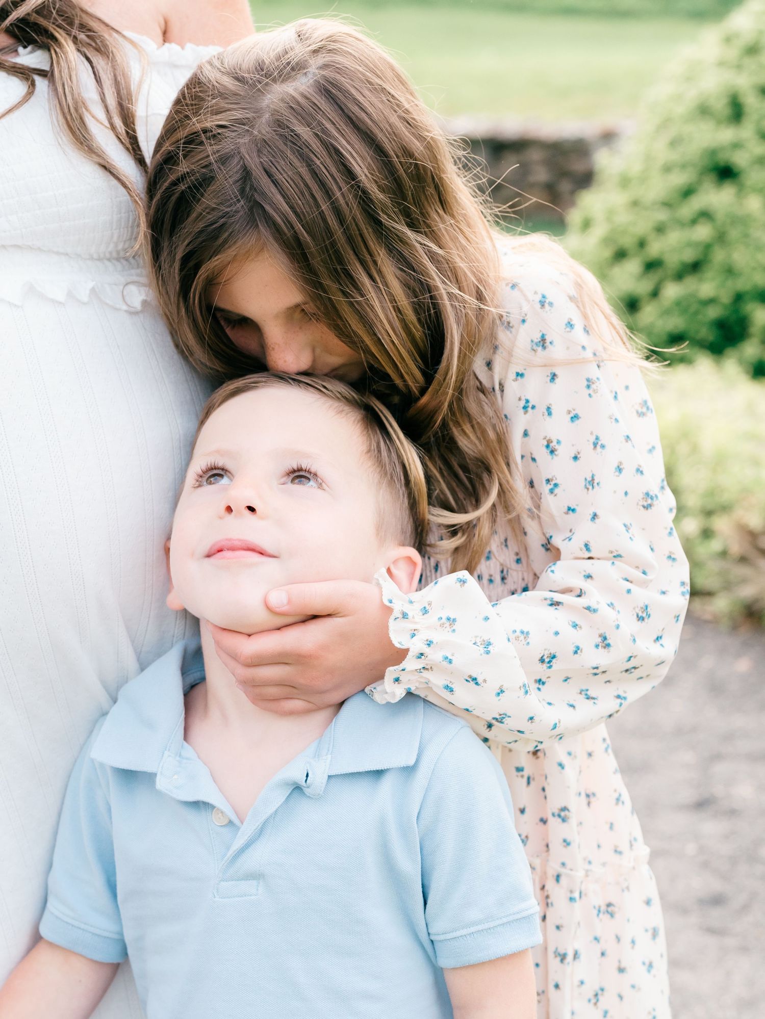 A girl kisses her brother's forehead.