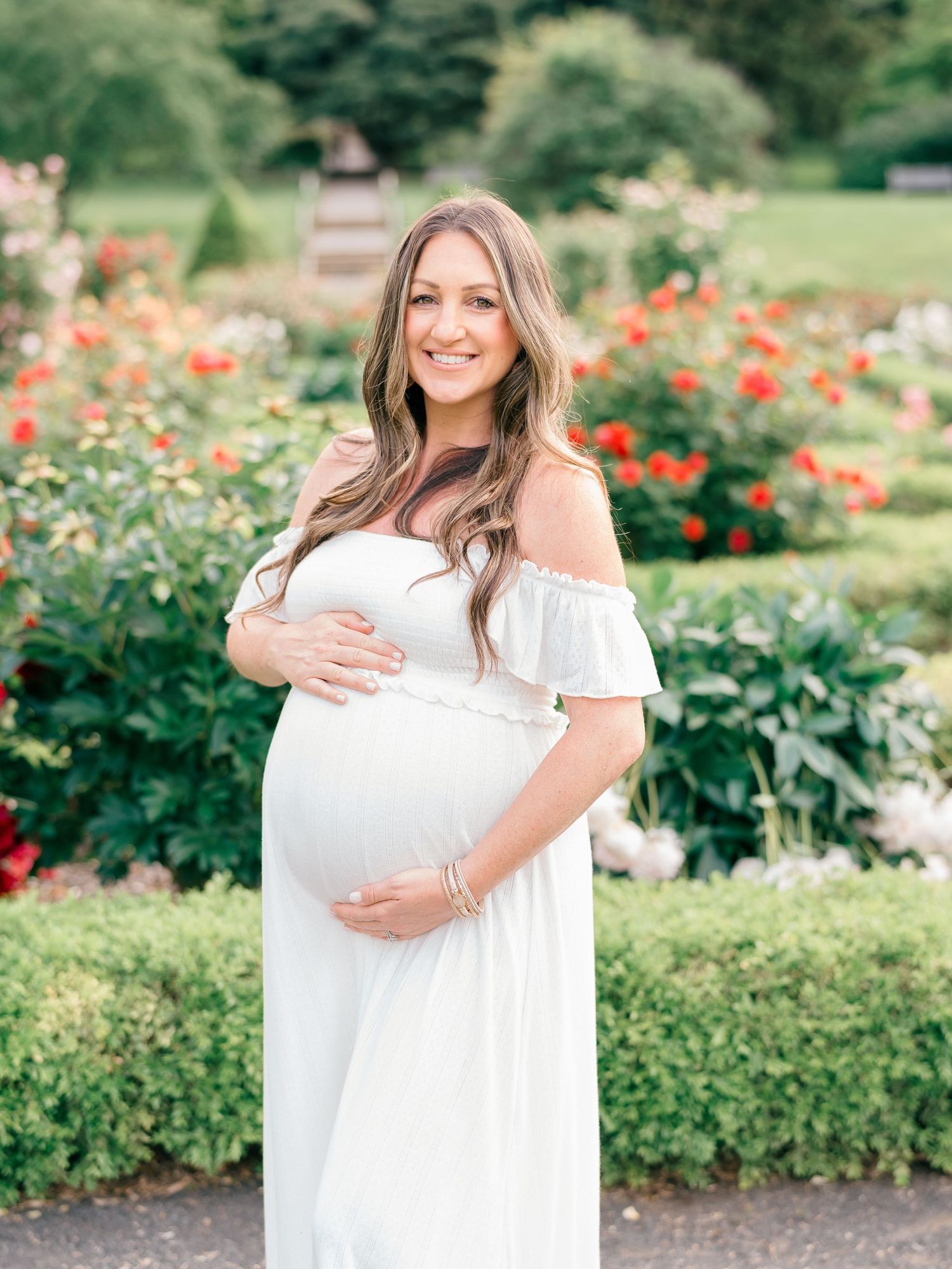 Peaceful smile on a pregnant woman’s face as she stands in the winding garden paths.