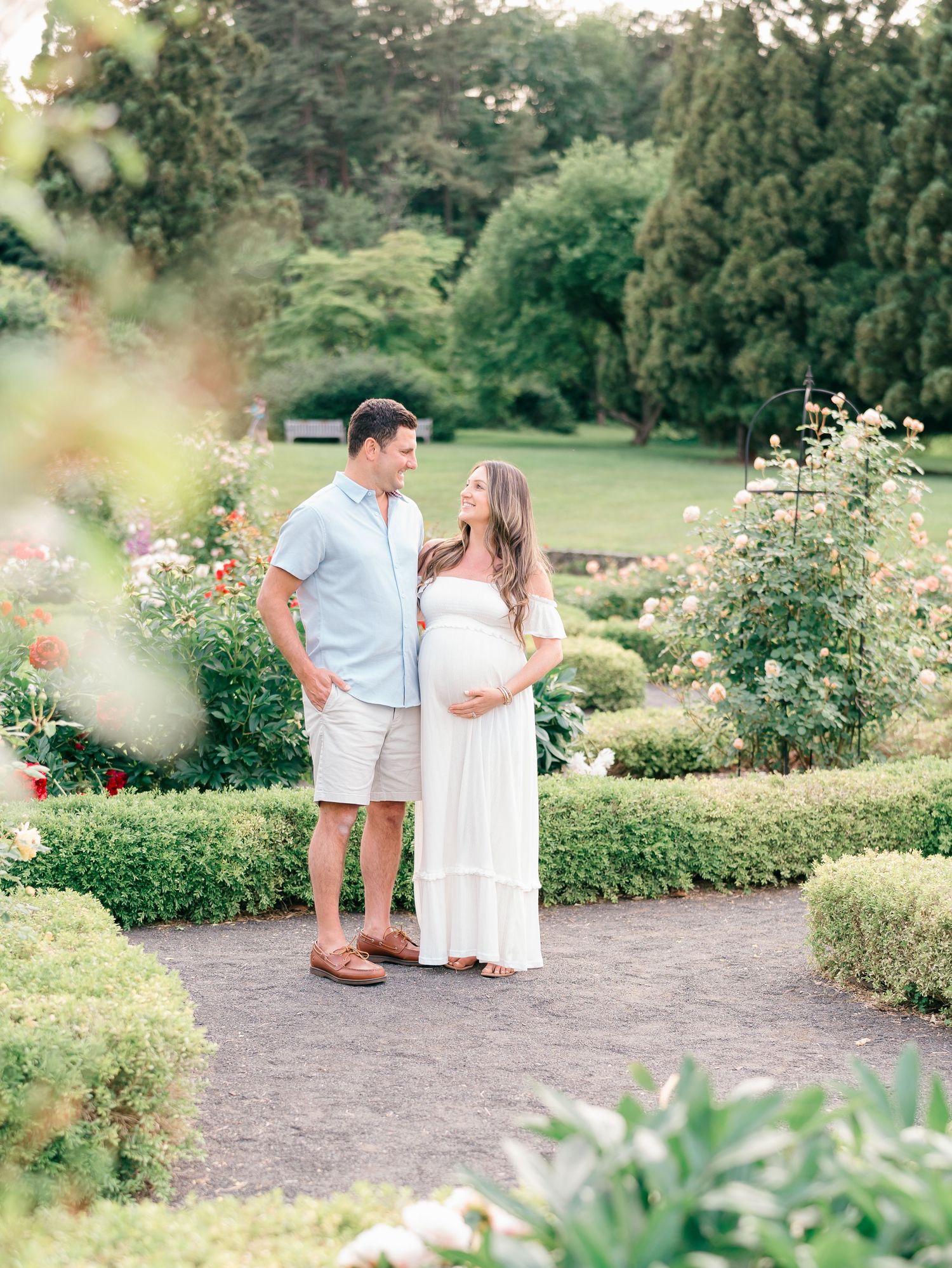 Pregnant woman and husband framed by lush ferns and vibrant foliage at Deep Cut Gardens.