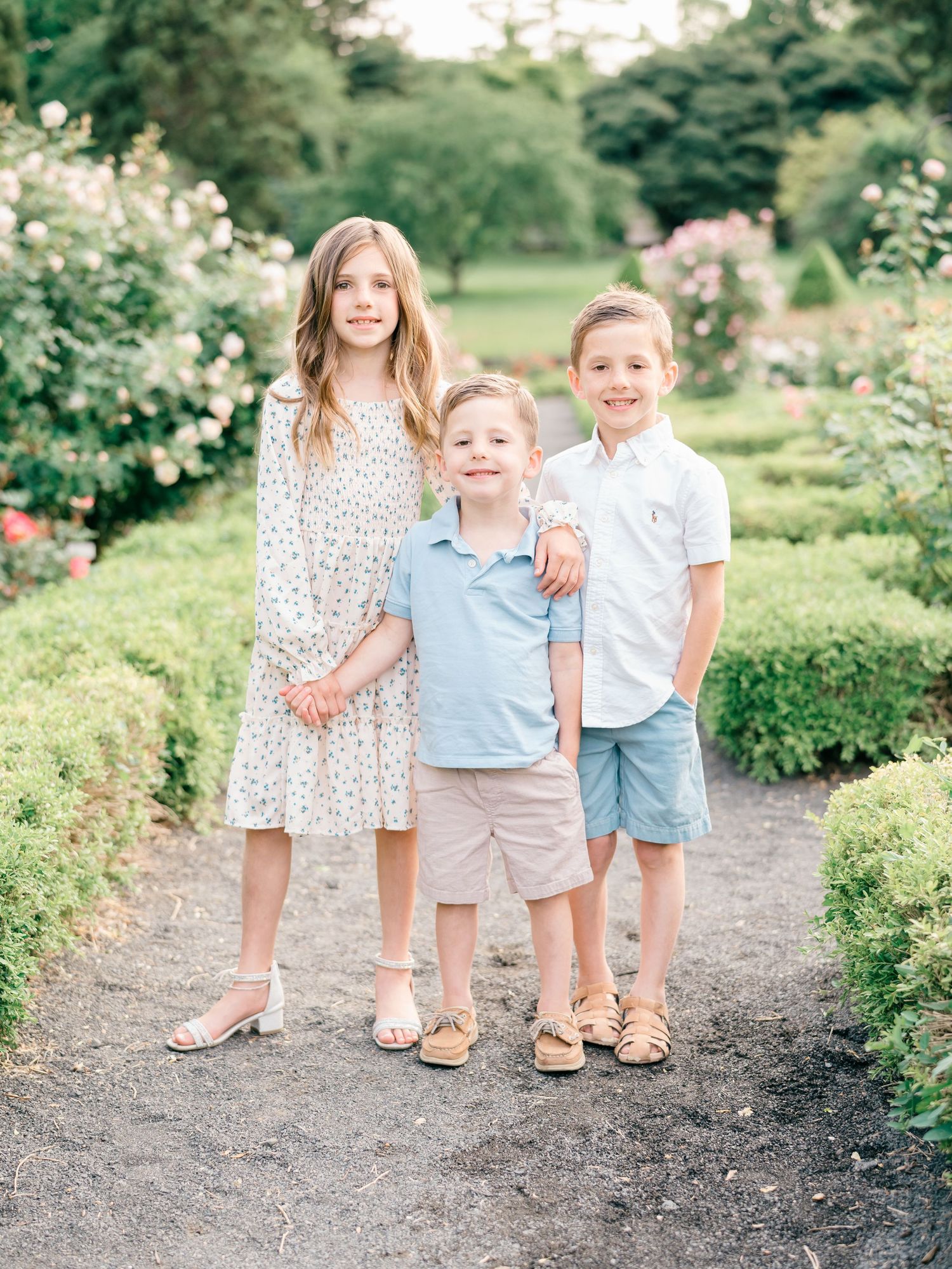 Three children in a garden in Middle Town NJ pose for a photo by Lauren Marie Photography.