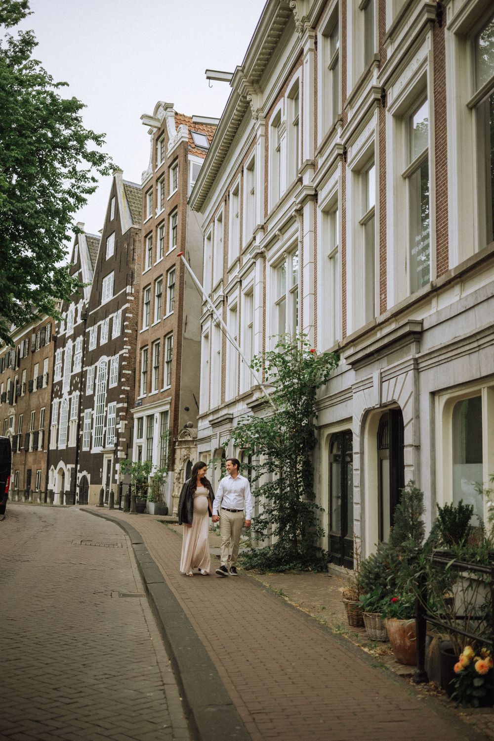 Charming sloped street in Amsterdam with traditional Dutch row houses and cobblestones.