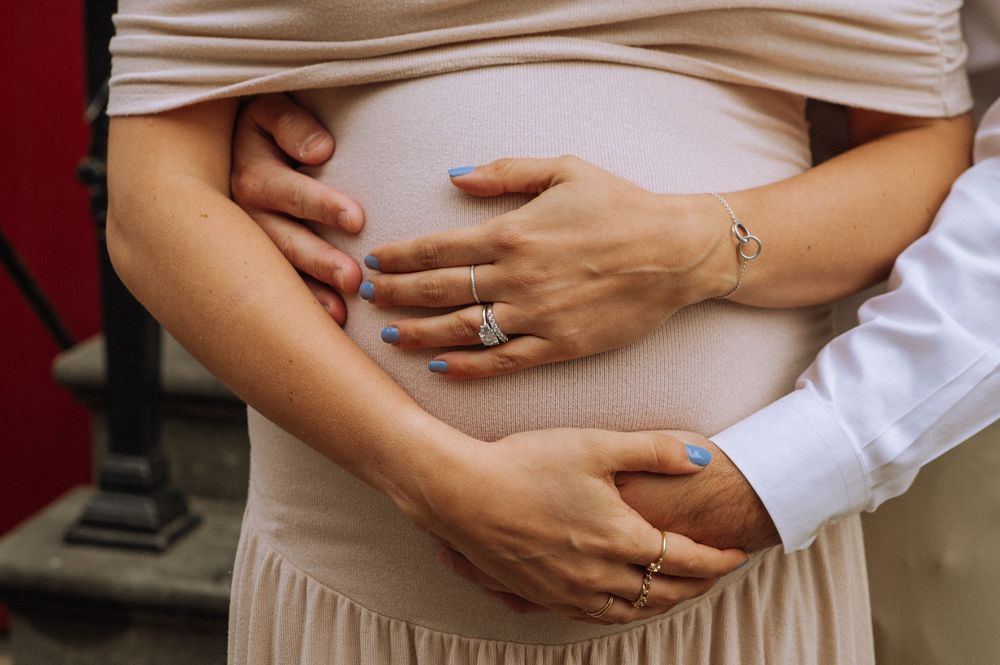 Close-up of hands tenderly cradling a pregnant belly in a romantic maternity moment.