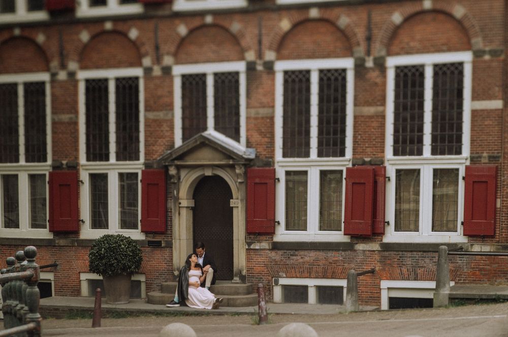 Traditional Dutch brick building exterior with white-framed windows and red shutters.