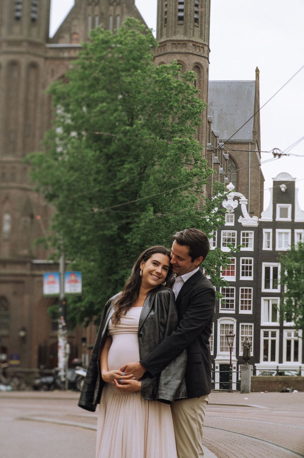 A romantic couple embraces near a historic church building in Amsterdam's city center.