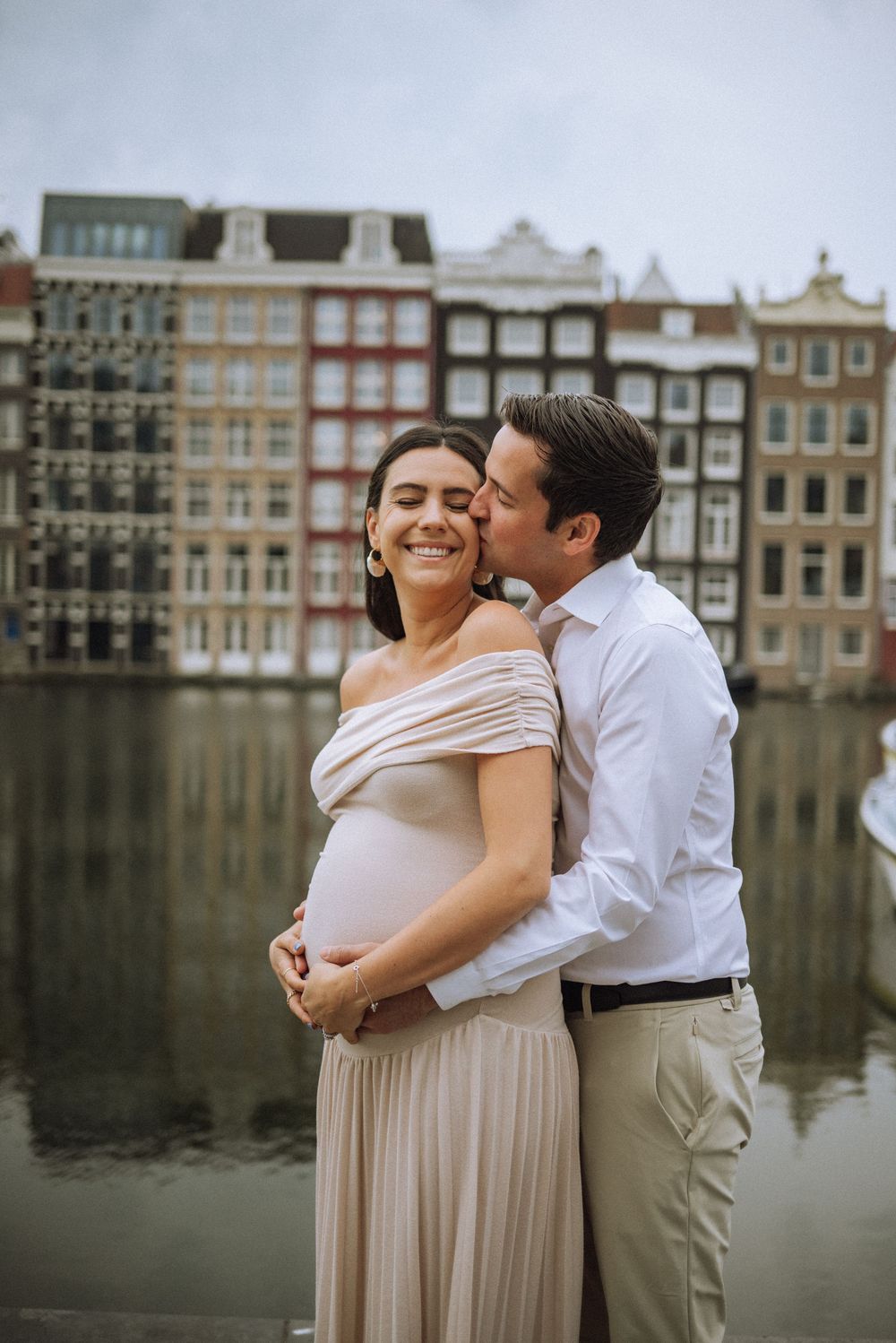 Romantic maternity photoshoot in front of traditional Amsterdam canal houses.