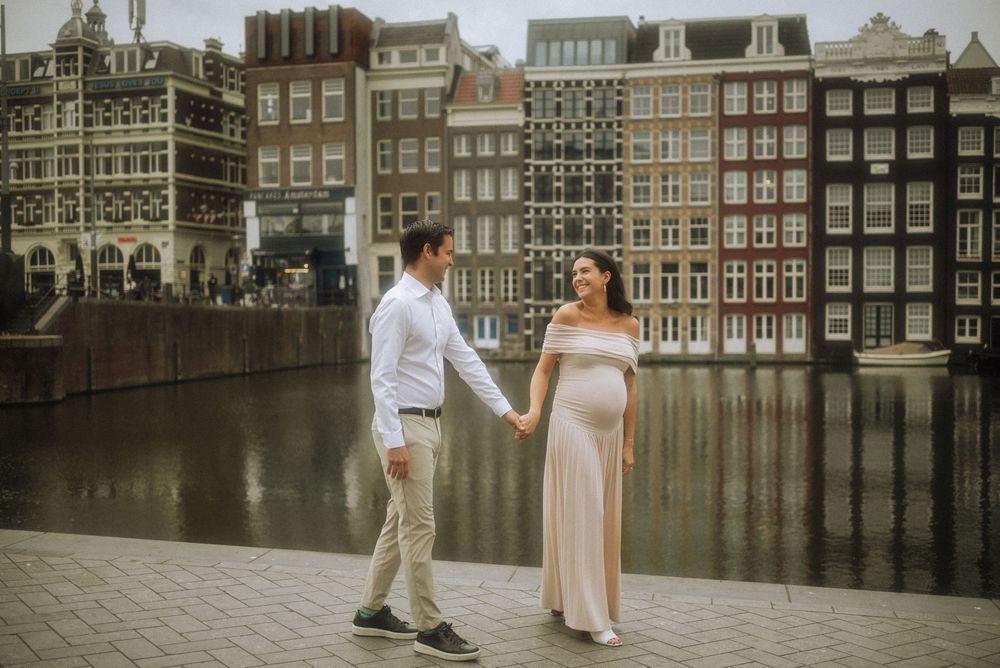 Romantic couple photoshoot along Amsterdam's iconic canals with historic Dutch architecture in the background.