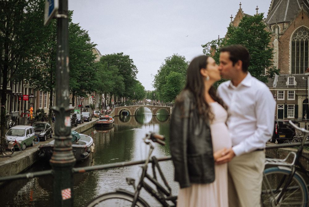 Scenic Amsterdam canal with traditional Dutch houses and trees lining the waterway.