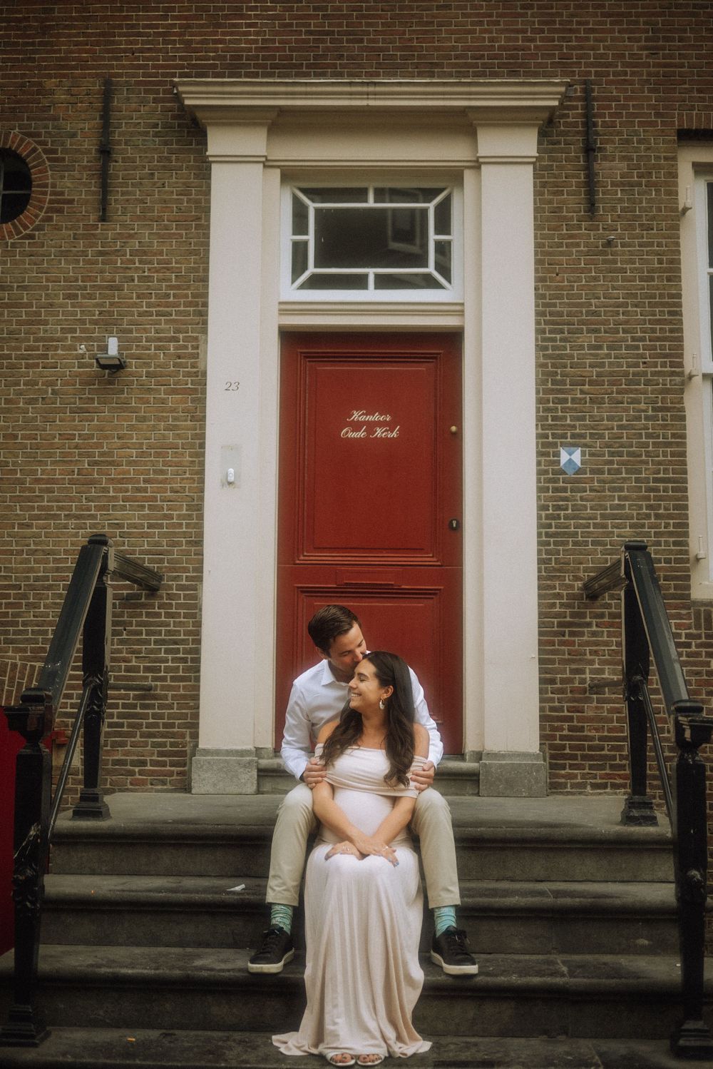 Romantic moment captured on historic brick steps with red doors in the background.