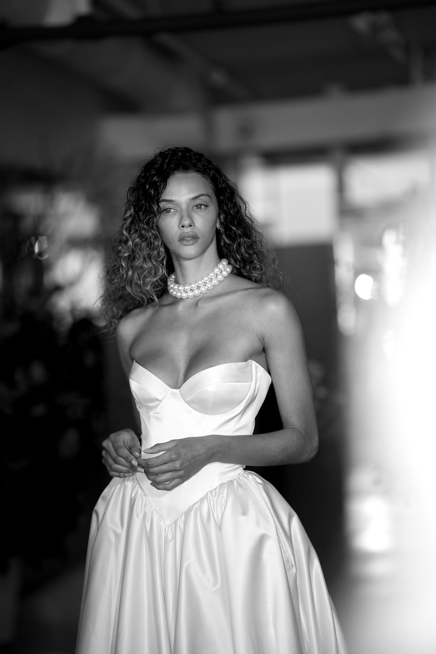 A model in a flowing white gown poses during a professional photoshoot.