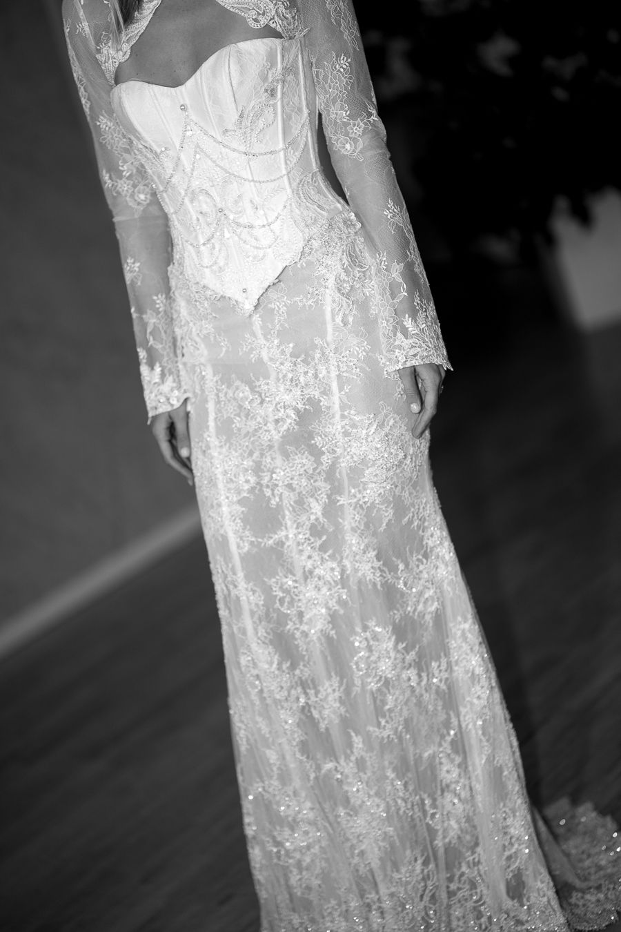 Black and white photograph showcasing intricate lace details on a flowing wedding gown.