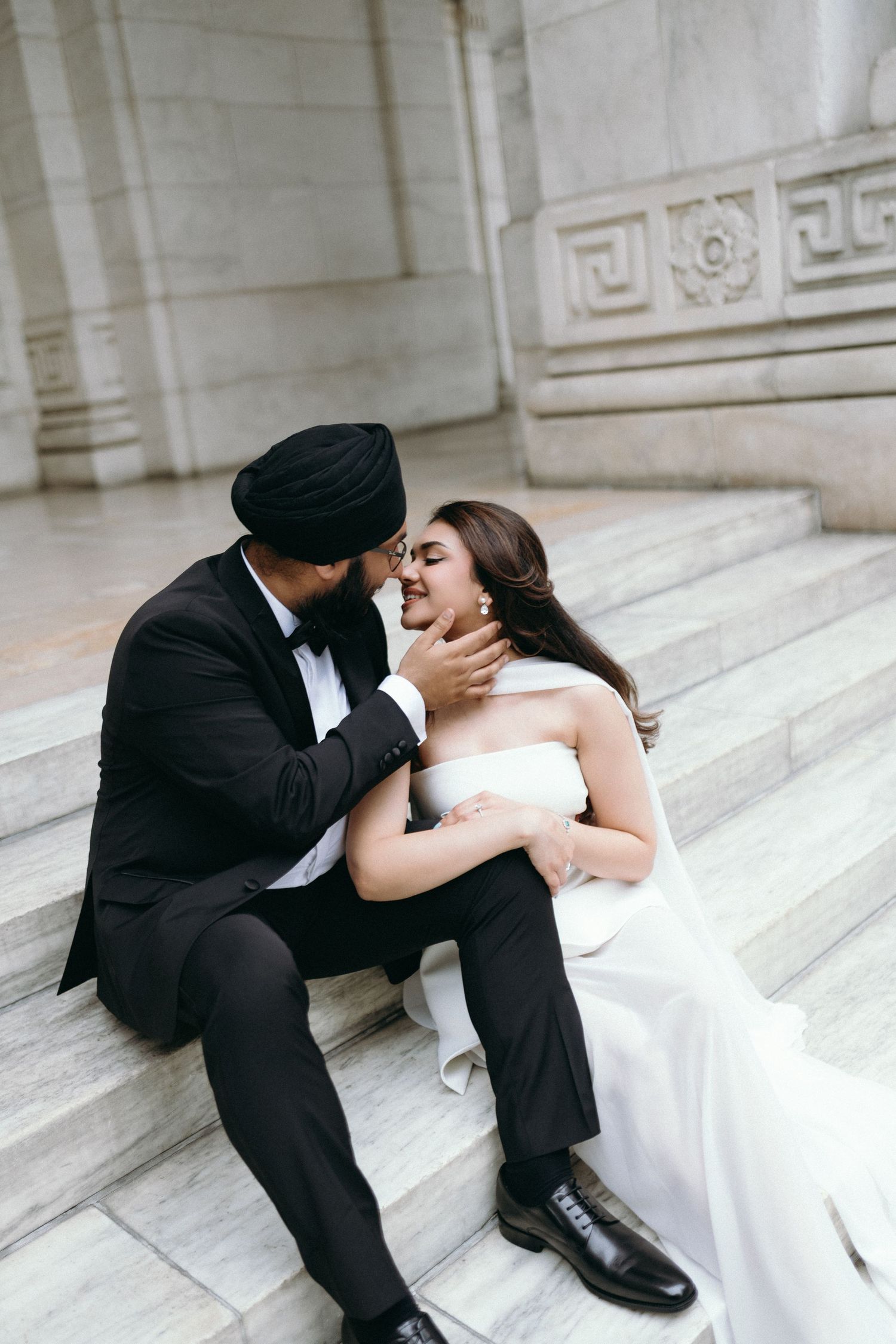 Elegant wedding couple walks through white marble arches in a historic building creating a romantic architectural scene.