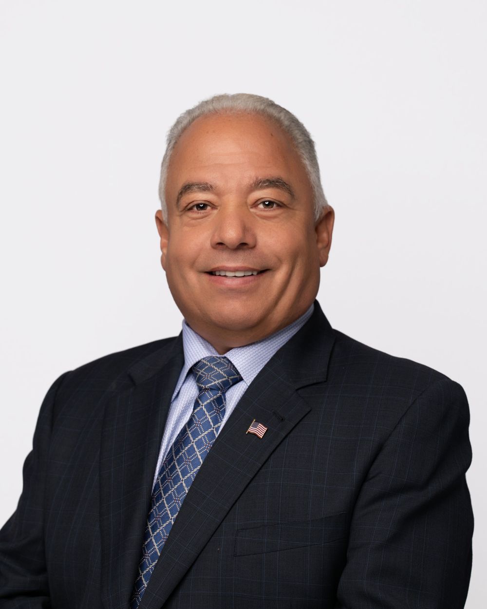Business portrait series showing a person in dark suit and blue tie against white backdrop.