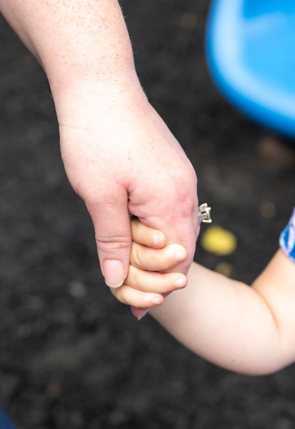 Close-up sequence of small hands holding each other in solidarity against a dark background.