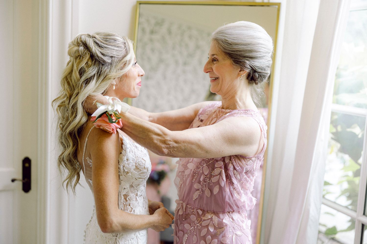 A series of getting ready photos showing tender moments between people in soft pink dresses in a sunlit room.